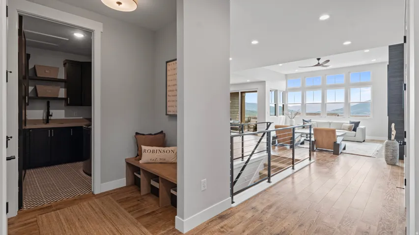 Entry hall with wood-finish flooring throughout, with a built-in wooden bench as you enter from the garage or front door.  The laundry room, featuring dark cabinetry, is located here as well.