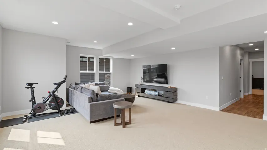 Spacious recreation room featuring recessed lighting, light-toned carpeting, and a window with blinds