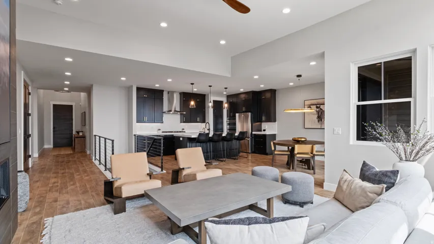 Open-concept living area with wood-finish flooring, recessed lighting, and a modern kitchen featuring dark cabinetry and light countertops