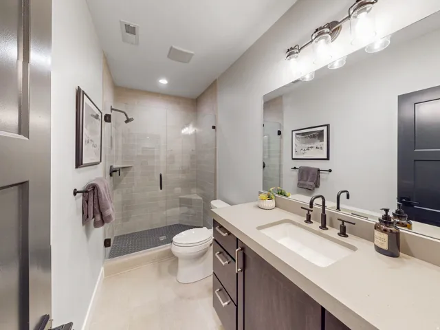 Second lower level bathroom (Bath #4) is a contemporary featuring a dark wood-finish vanity with an integrated sink and light-toned countertop