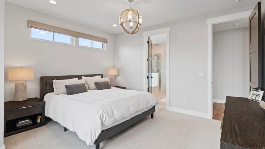 Spacious Primary suite featuring light-colored carpeting, recessed lighting, and a contemporary spherical chandelier