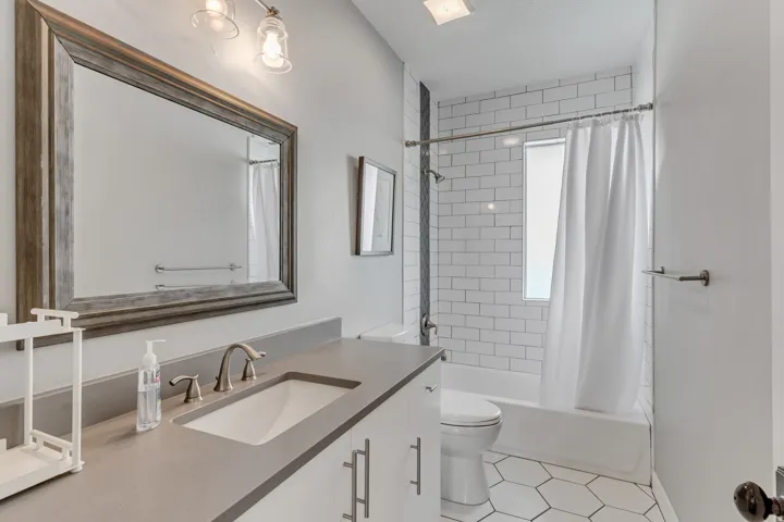 Contemporary bathroom featuring a vanity with an integrated sink and brushed nickel faucet, a large framed mirror, and two-light fixture