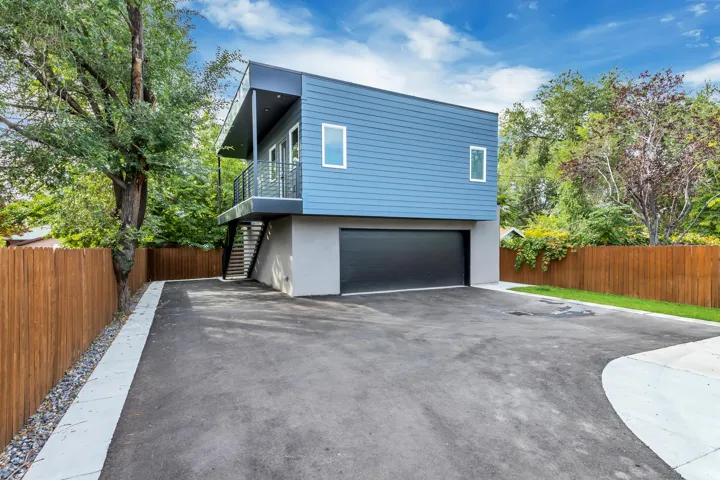 Modern multi-level exterior with blue siding and a dark garage door