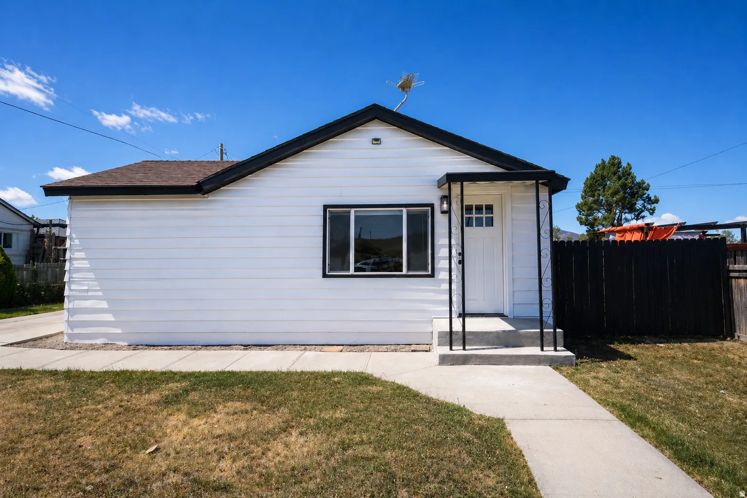 Exterior featuring white siding with black trim, a gabled roof, and a covered entryway