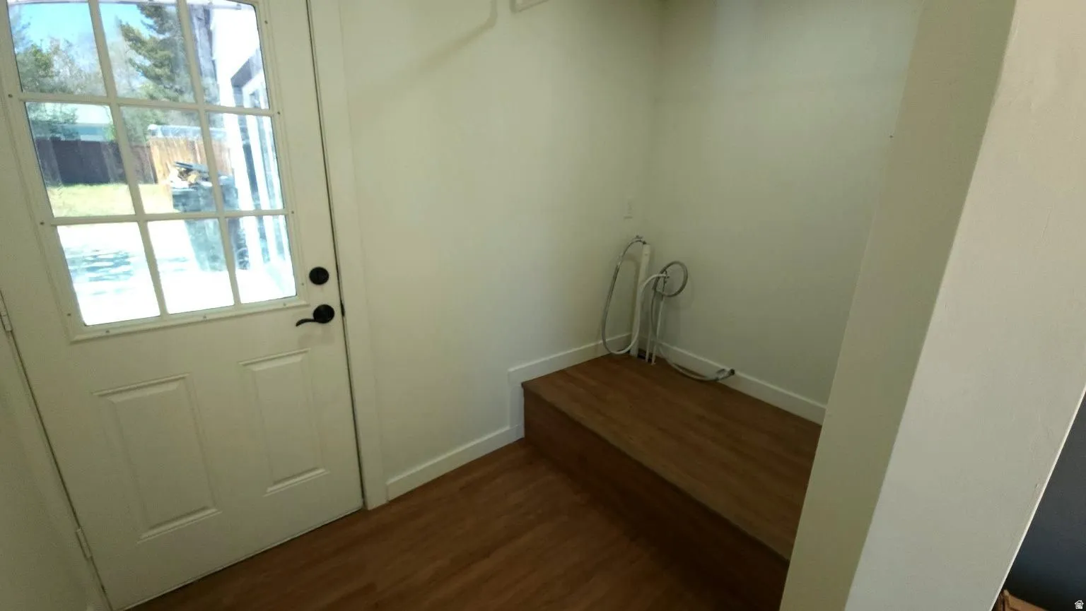 Utility space featuring a glass-paned door, wood-finish flooring, and a built-in wood-finish bench