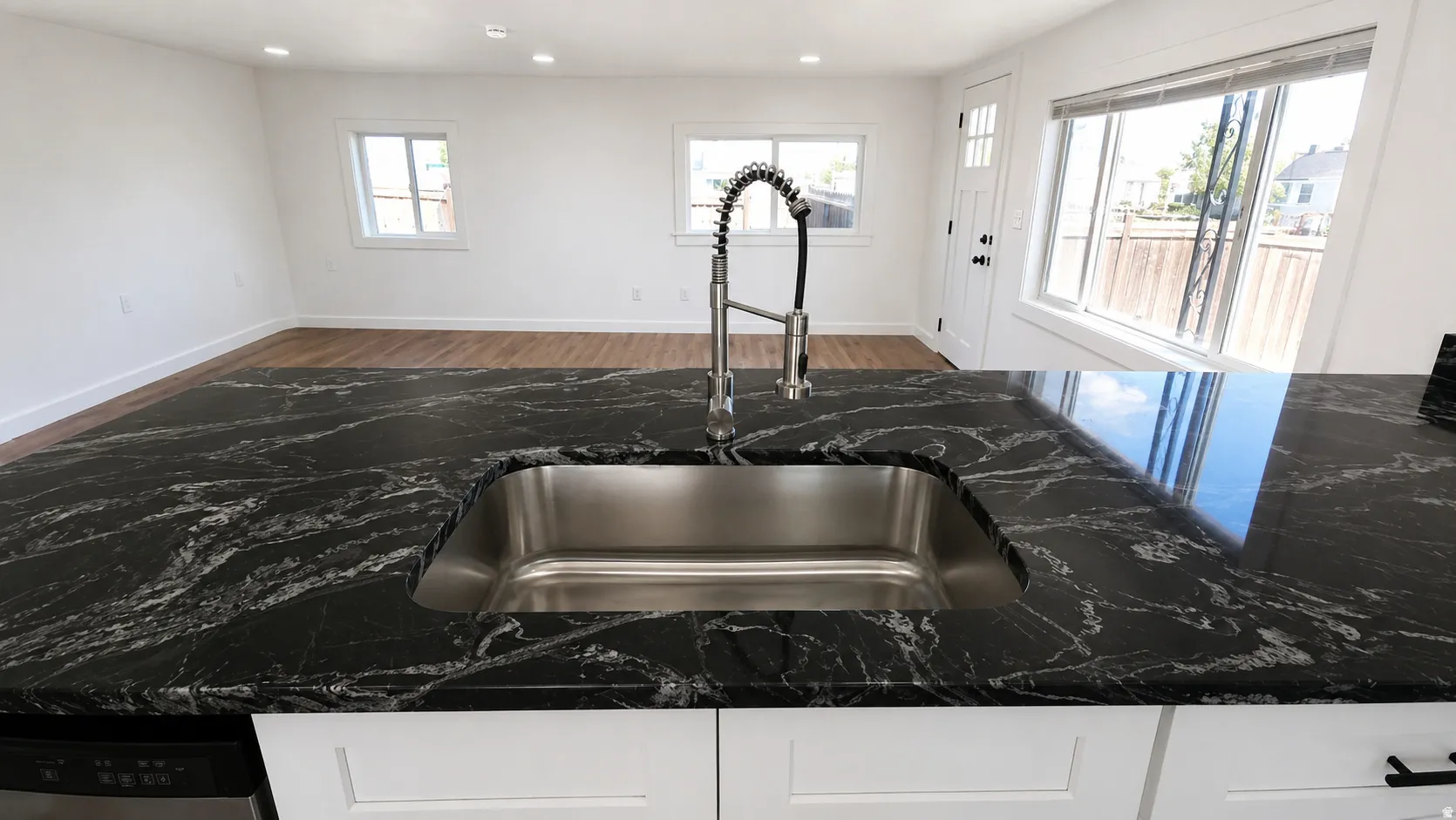 Black countertop with white veining, featuring an undermount stainless steel sink and a gooseneck faucet