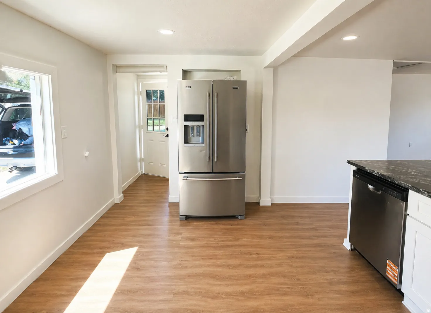 Open-concept space featuring wood-finish flooring, recessed lighting, and a stainless steel refrigerator