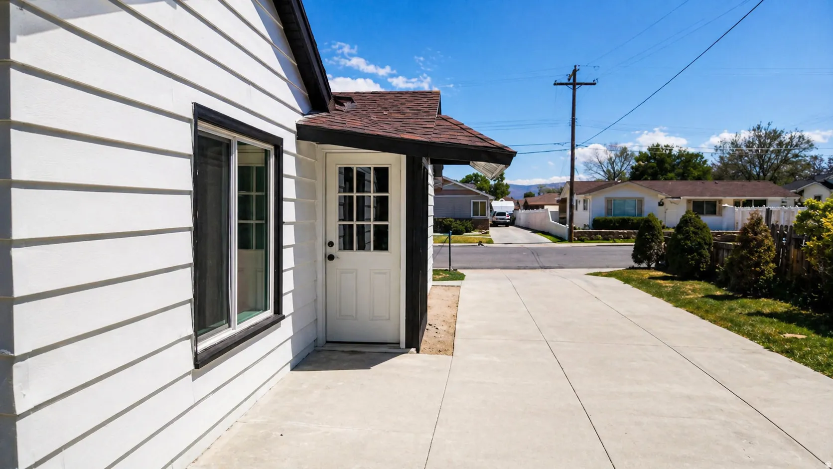 White horizontal siding exterior with dark trim and a brown shingle roof