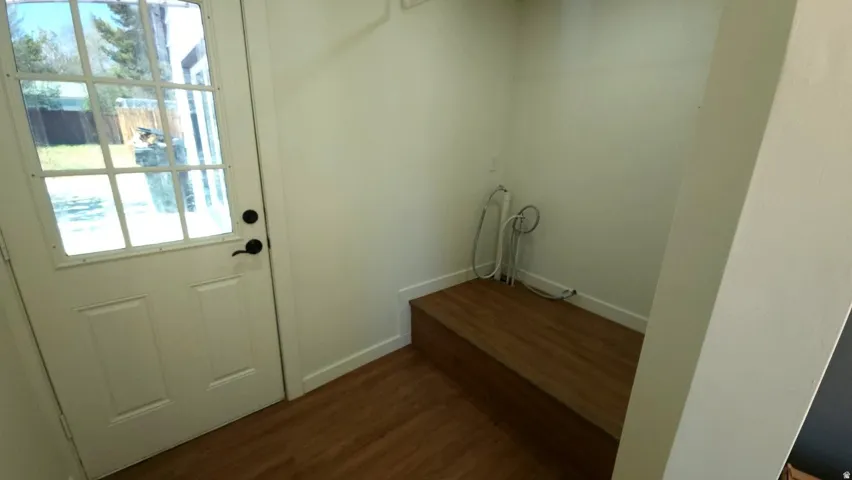 Utility space featuring a glass-paned door, wood-finish flooring, and a built-in wood-finish bench
