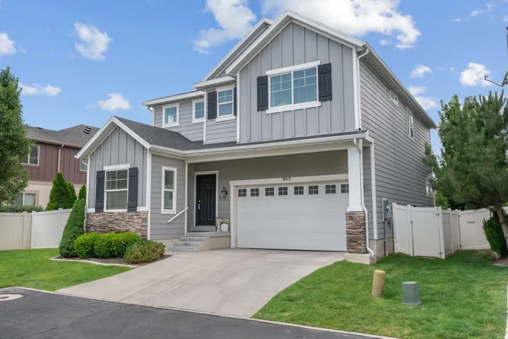 Contemporary residence featuring a two-car garage, stone accents, board and batten siding, horizontal siding, and a fenced yard
