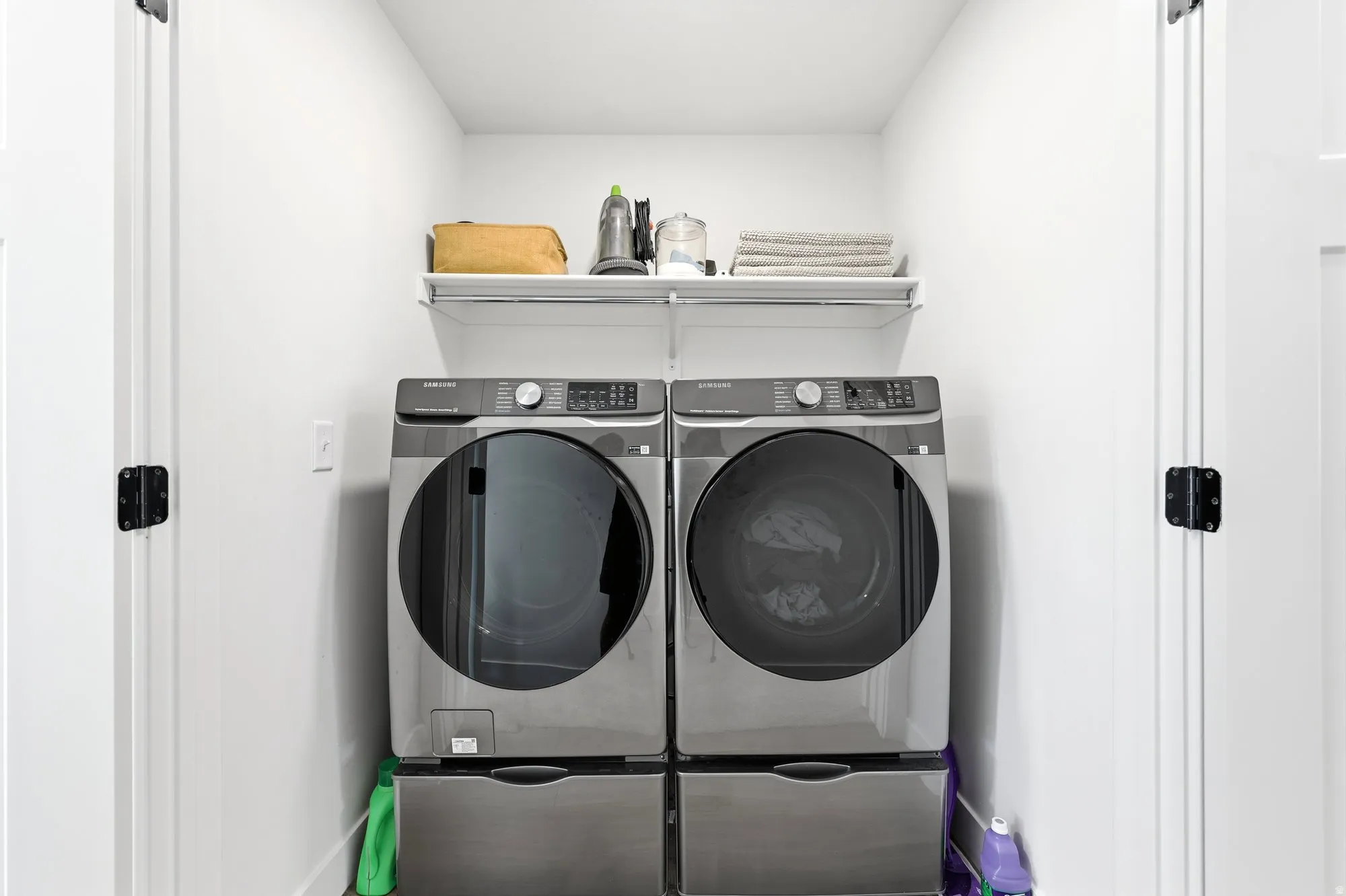 Dedicated laundry area with white walls and a wire shelf