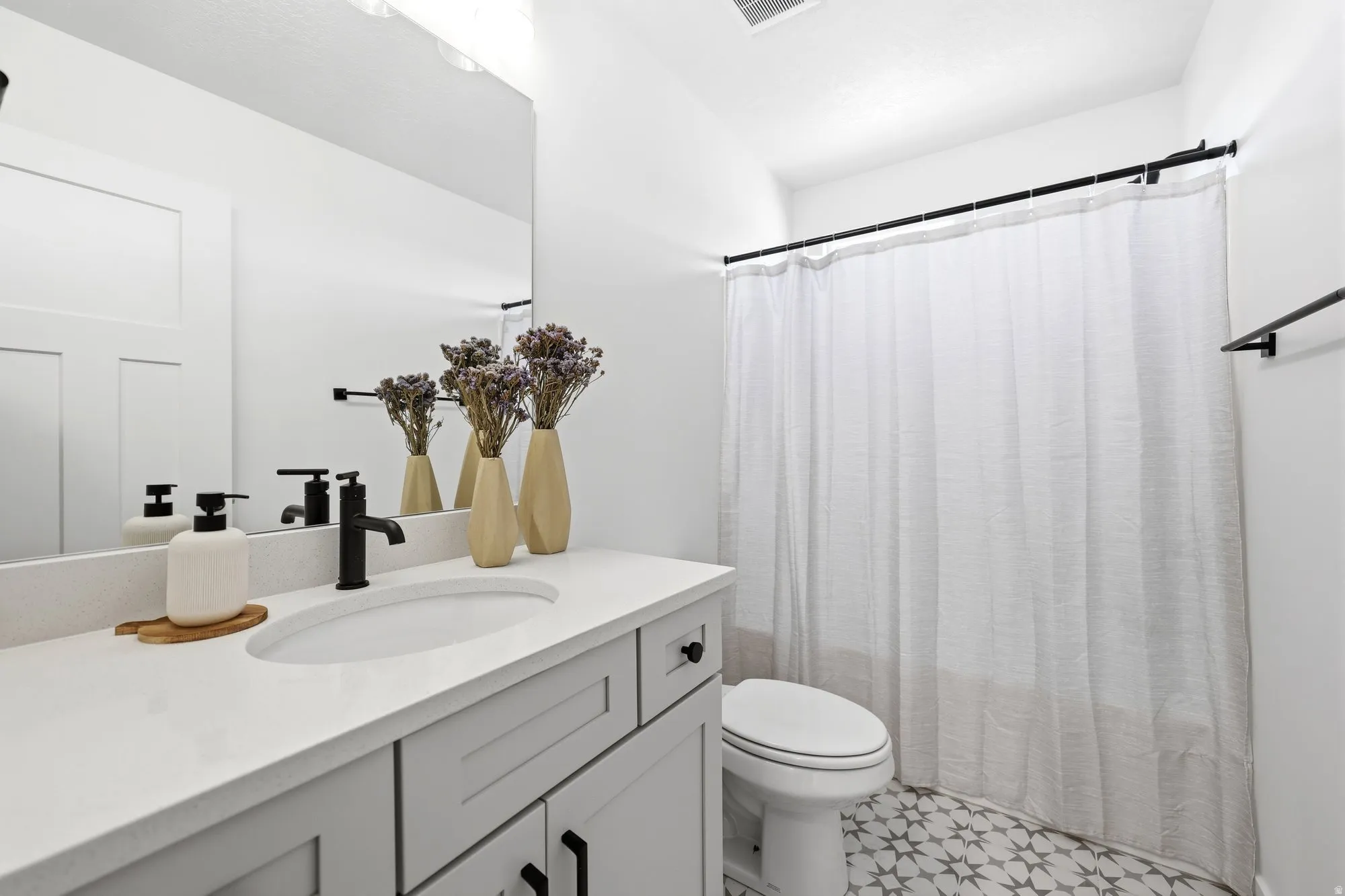 Bathroom featuring a single vanity with a white countertop, undermount sink, and matte black faucet