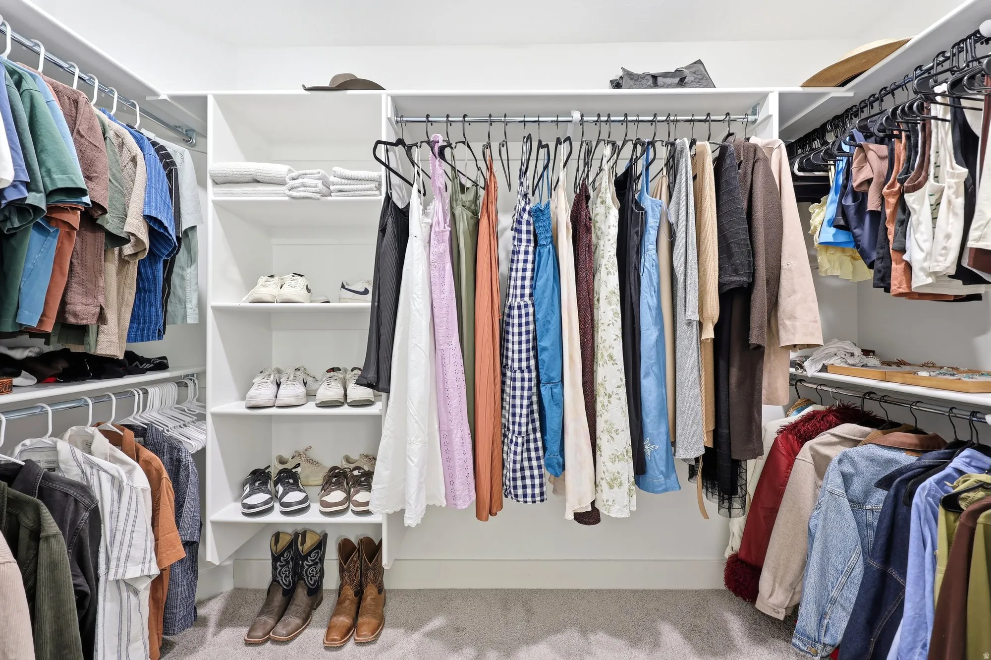 Custom closet system featuring white shelving, multiple hanging rods, and integrated shoe storage