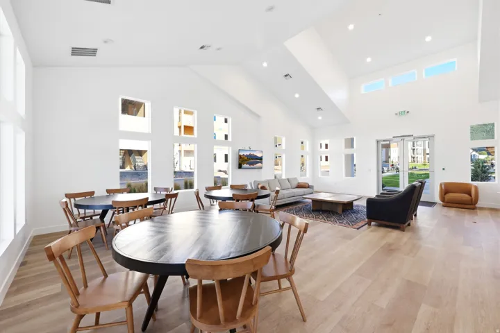 Spacious common area featuring vaulted ceilings, ample natural light from multiple window groupings, recessed lighting, and wood-finish flooring
