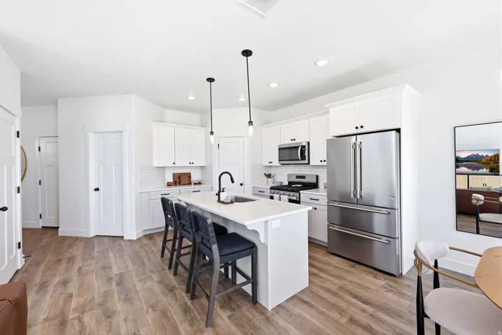 Modern kitchen featuring white shaker cabinetry, stainless steel appliances, a white subway tile backsplash, and a central island with integrated seating