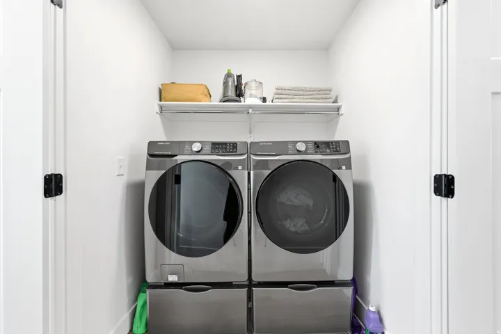 Dedicated laundry area with white walls and a wire shelf