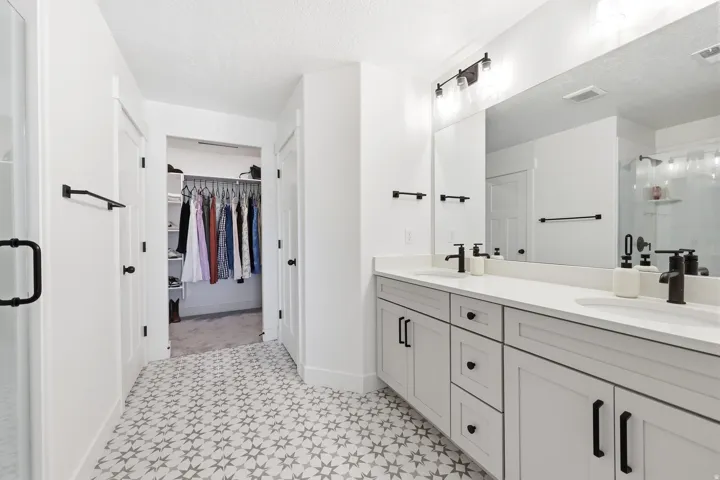 Spacious bathroom featuring a dual vanity with white countertops, light gray cabinetry, and matte black fixtures