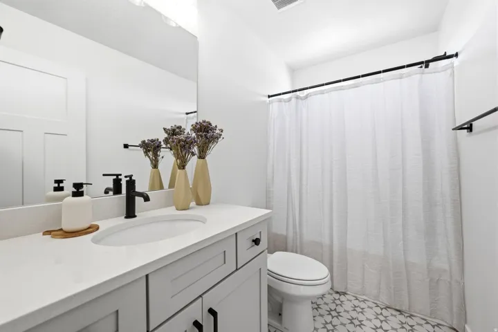 Bathroom featuring a single vanity with a white countertop, undermount sink, and matte black faucet