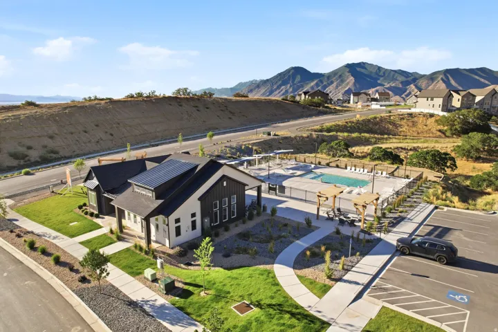 Modern-style community building featuring dark siding and light exterior finishes, solar panels, and a manicured lawn