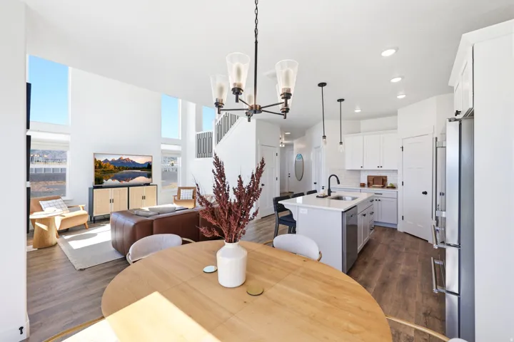 Open-concept living area featuring high ceilings, wood-finish flooring, and abundant natural light from tall windows