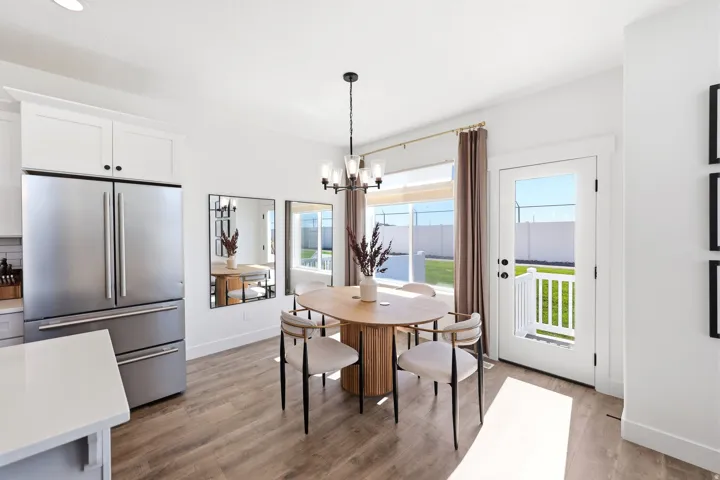 Dining area featuring wood-finish flooring, a contemporary chandelier, and white trim