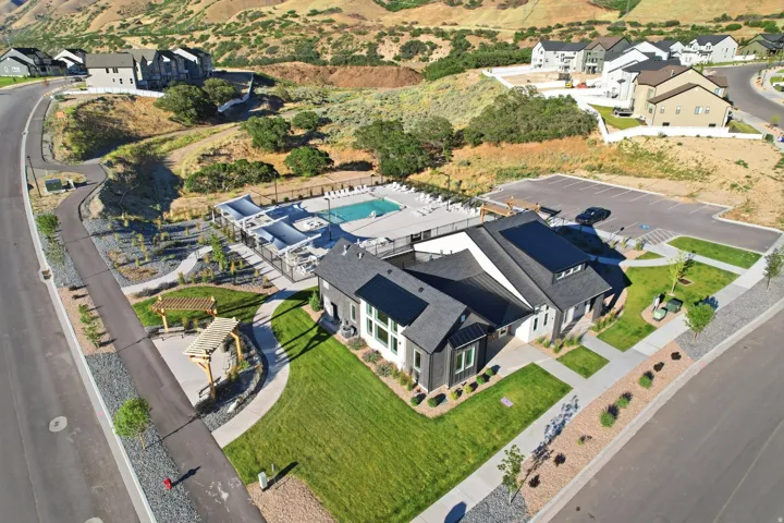 Community clubhouse featuring a dark gray exterior, adjacent parking, outdoor pool, and a shaded pergola area