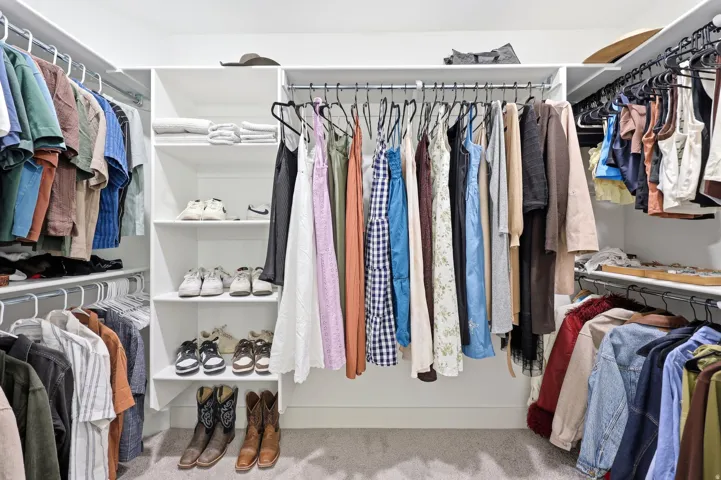 Custom closet system featuring white shelving, multiple hanging rods, and integrated shoe storage