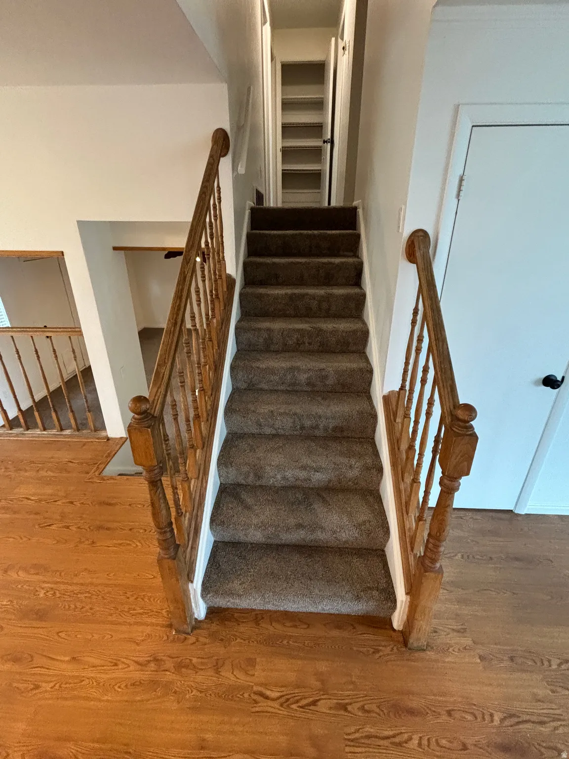 Carpeted staircase with wood banister and balusters