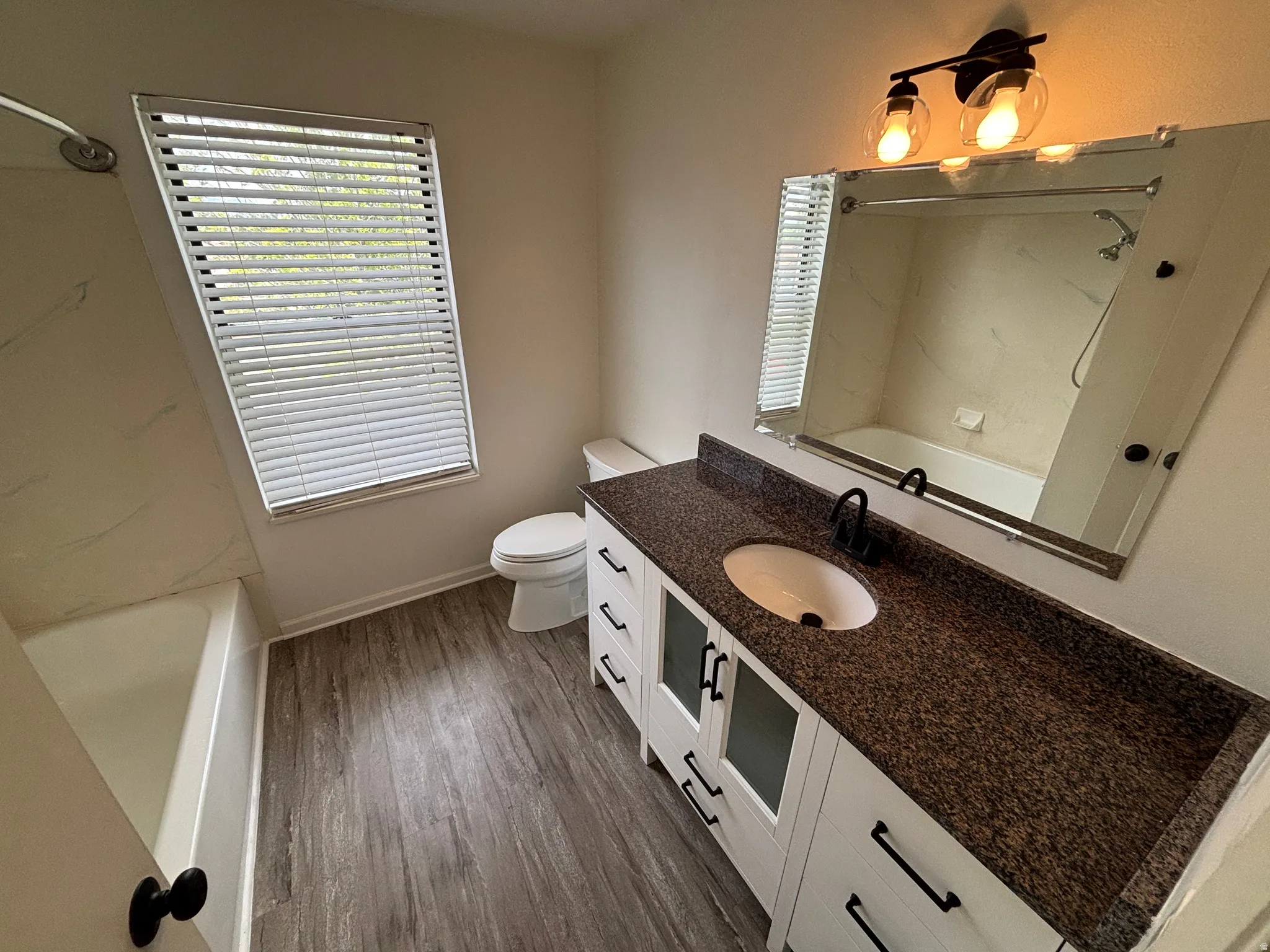 Modern bathroom vanity with a speckled countertop, white cabinetry with black hardware, and an oval undermount sink with a matte black faucet