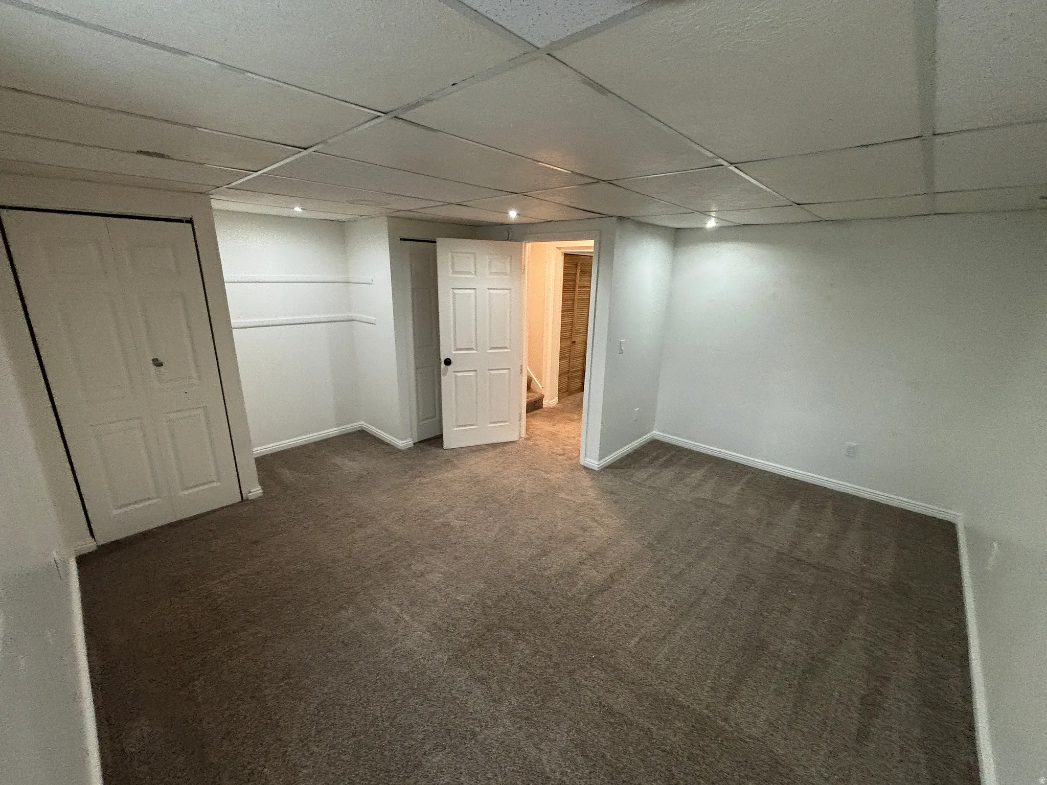 Carpeted room with white walls and a drop ceiling