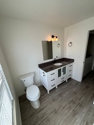 Bathroom featuring a white vanity with a dark countertop, an undermount sink, and black fixtures