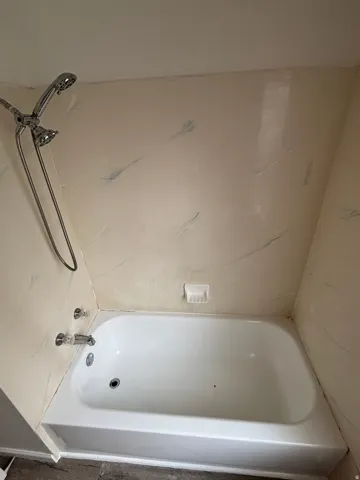 White bathtub with chrome fixtures and an integrated soap dish