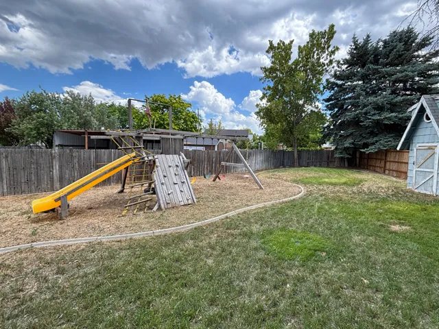 Expansive backyard with established trees, a storage shed, and perimeter fencing