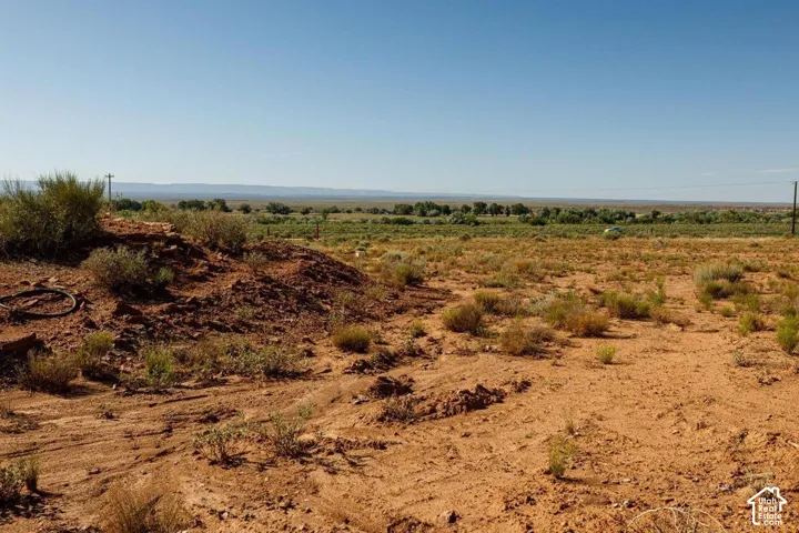 Expansive desert landscape featuring reddish-brown earth and sparse low-lying vegetation