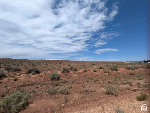 Expansive open land featuring red earth and scattered brush
