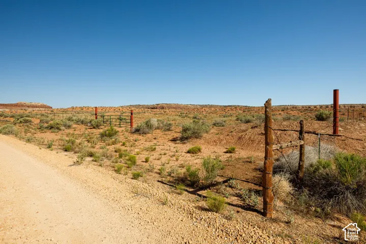 Expansive desert landscape featuring a dirt road and a fenced boundary