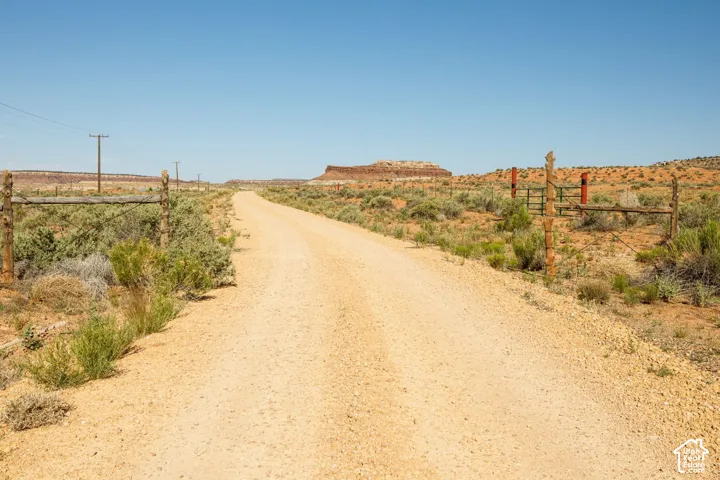 Gravel road extending into the distance, bordered by wood and wire fencing