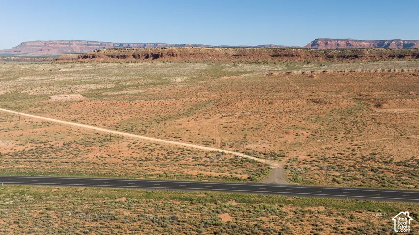 Expansive desert landscape featuring a paved road with an unpaved access path