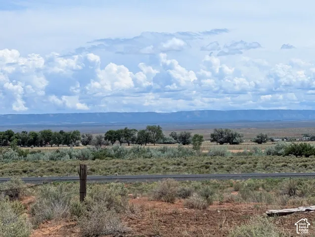 Expansive desert landscape featuring distant mesas and a cloud-filled sky