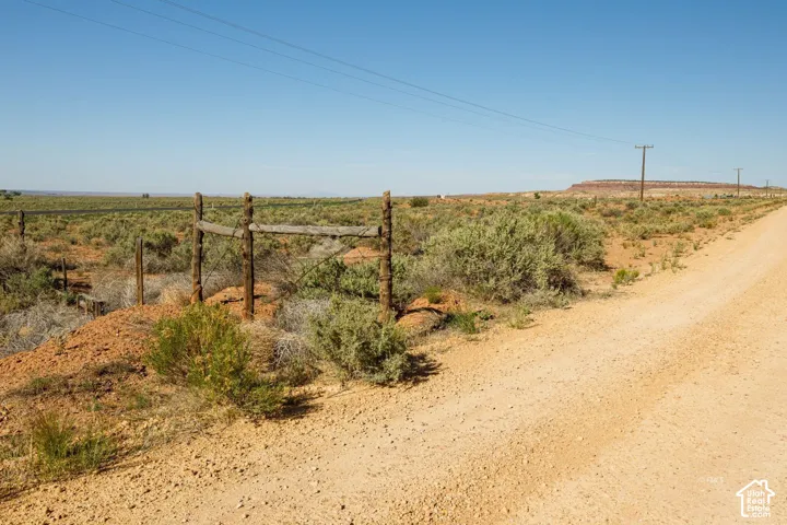 Unpaved road with natural vegetation and a distant mesa under a clear sky