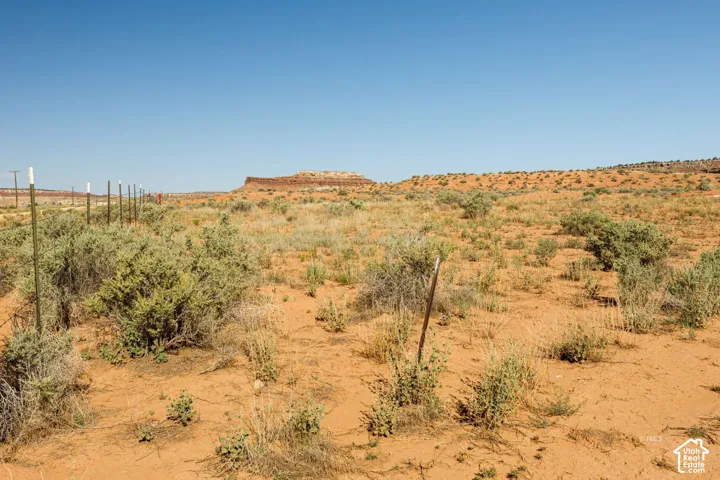 Expansive desert landscape featuring natural scrub brush and sandy terrain