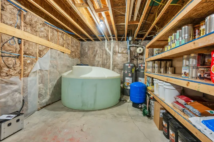 Unfinished basement space featuring exposed wooden ceiling joists, insulated walls, and a concrete floor