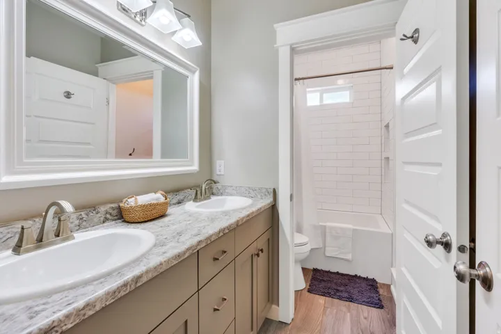 Full bathroom featuring a double vanity with two undermount sinks, speckled countertop, and brushed nickel fixtures