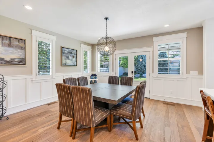Spacious dining area featuring wood-finish flooring, white wainscoting, and recessed lighting