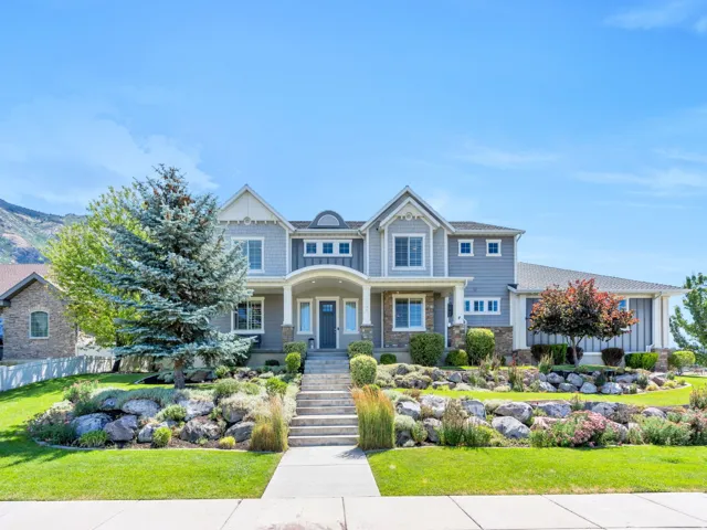 Traditional-style home featuring gray siding, stone accents, multiple gables, a covered entry, and a prominent front door