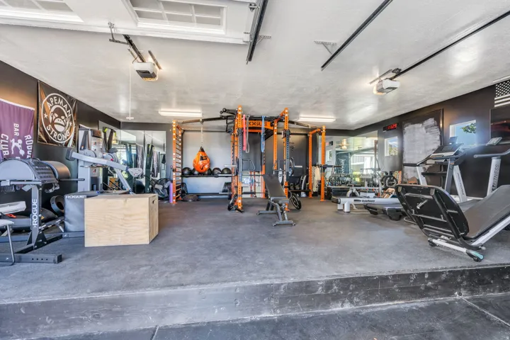Dedicated fitness space featuring rubber flooring, dark wall finishes, and integrated lighting