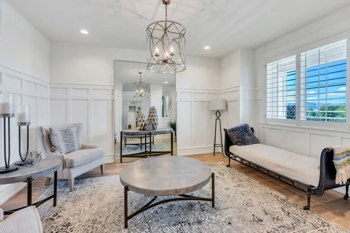 Living area featuring wainscoting, wood-finish flooring, and white plantation shutters