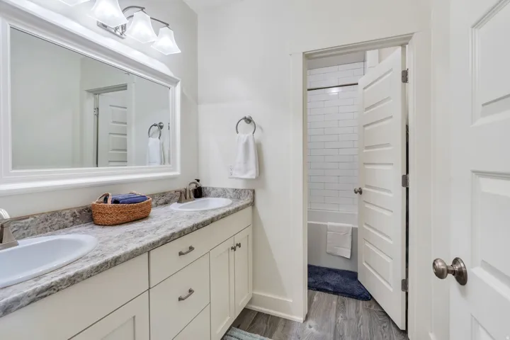 Dual sink vanity with white cabinetry, speckled countertop, and brushed nickel hardware