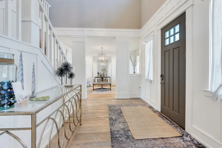 Foyer featuring a dark wood front door with glass panes, wood-finish flooring, and white wainscoting