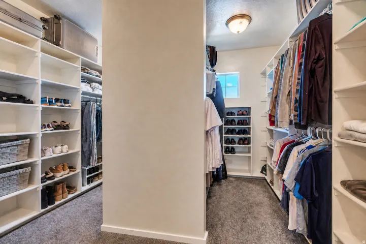 Walk-in closet featuring extensive built-in shelving, hanging rods, and a window for natural light